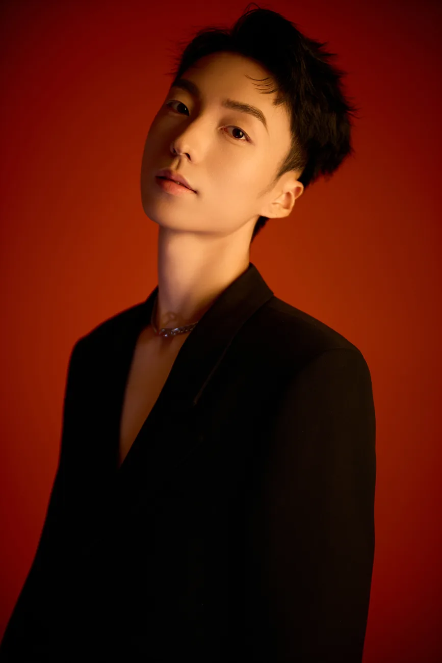 Half-length black suit portrait of Z·GY against red